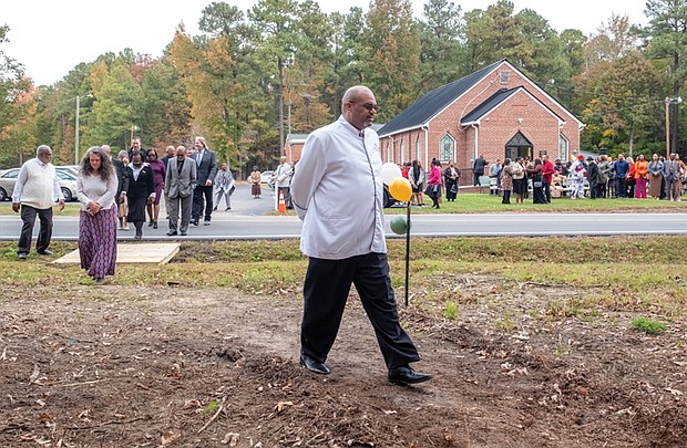 Groundbreaking ceremony commemorates Brown Grove School-The Brown Grove School Memorial Committee held a groundbreaking ceremony Oct. 26 for a new memorial across from Brown Grove Baptist Church in Ashland. The memorial honors the historic Brown Grove School, a two-room schoolhouse built in 1925 that educated African American children in grades 1–7 until it was destroyed by fire in 1942. The school served as a center of learning, pride, and resilience for the Brown Grove community. The Rev. Darius Beecham, pastor of The Historic Brown Grove Baptist Church leads church and community members across the street for the groundbreaking.(Sandra Sellars/Richmond Free Press)