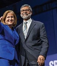 Sen. Ghazala Hashmi, with her husband, Azhar Rafiq, waves to supporters after being elected Virginia’s next lieutenant governor.(Julianne Tripp Hillian/Richmond Free Press)
