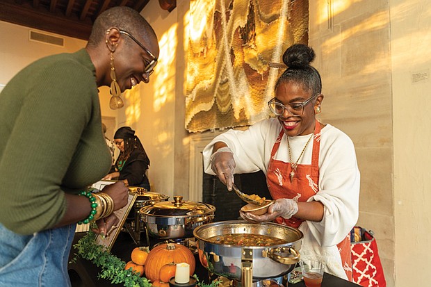 Museum makes way for fashion, food and culture-The Afro-Vegan Social at the Branch Museum of Design on Sunday, Nov. 9, brought together food, fashion and culture. Organized by For the Fem in You, the event highlighted healthy food access while celebrating futuristic African culture and style. Guests enjoyed a set from DJ Chey Butta + Ease, a fashion show featuring multiple designers, a pop-up shop, and vegan tastings from local chefs and restaurants. Shayola Binta serves vegan pumpkin stew to Ariane McKeller. (Julianne Tripp Hillian)