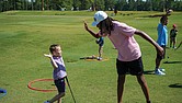 A First Tee participant shares a high-five with a younger student after a lesson on the golf course. The chapter recently received the Barbara A. Douglas and Dr. William J. Powell Community Award for its work expanding access to golf and character education for underserved youth.