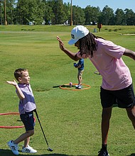 A First Tee participant shares a high-five with a younger student after a lesson on the golf course. The chapter recently received the Barbara A. Douglas and Dr. William J. Powell Community Award for its work expanding access to golf and character education for underserved youth.