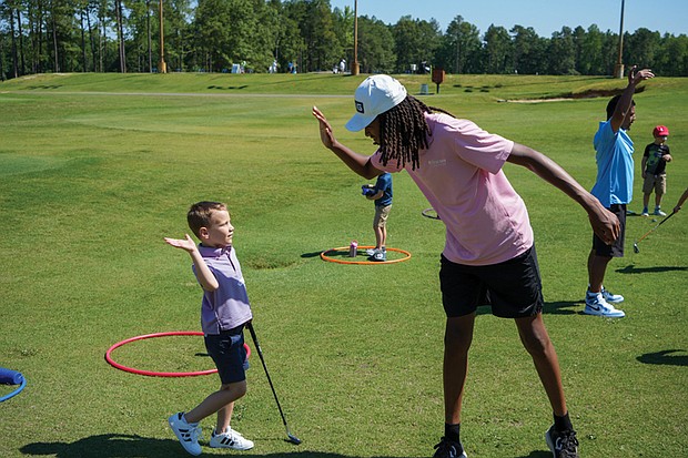 A First Tee participant shares a high-five with a younger student after a lesson on the golf course. The chapter recently received the Barbara A. Douglas and Dr. William J. Powell Community Award for its work expanding access to golf and character education for underserved youth.