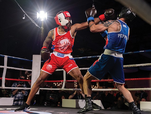 Police, firefighters duke it out for charity-Keivon Henderson of the Richmond City Firefighters, fighting out of the red corner, goes
glove to glove with Richmond Police’s Duane Peppel in the blue. Richmond City firefighters and police officers traded gloves for a good cause during River City Fight Night: Red Fight & Blue at River City Roll on Nov. 5. The charity boxing event raised funds for the Children’s Hospital Foundation, selected by the Fire Department, and the American Kidney Fund, chosen by the Police Department. (Julianne Tripp Hillian/Richmond Free Press)