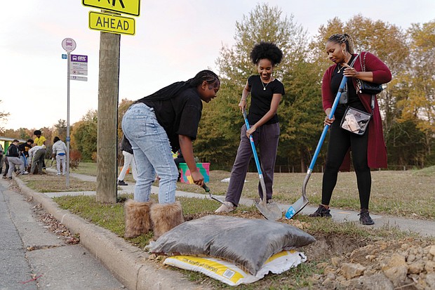 Cityscape Slices of life and scenes in Richmond- Aqiyla McMillan of RVA Rapid Transit, her daughter Kayden McMillan and her goddaughter Kasey Collins planted trees Wednesday, Nov. 12, at the bus stop at Fairfield Avenue and Kane Street as part of Richmond Tree Week. A recent inventory found that 36% of the city’s tree wells are empty, leaving about 44,000 missing trees. Environmental data analyst Melanie Del Pozo reported that 403 bus stops have at least one vacant tree well and 227 have none. Many are in neighborhoods where residents face higher heat exposure. Richmond Tree Week, held Nov. 1-8, included more than 30 free events. Activities featured volunteer plantings, tree giveaways, walking and biking tours and educational workshops. (Julianne Tripp Hillian/Richmond Free Press)