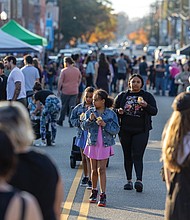Neighborhood pride shines at Brookland Park Fest-Brookland Park Fest filled the boulevard with music, art and food as residents and visitors gathered Sunday, Nov. 9 for the annual community celebration. The free event, organized by the Brookland Park Business Association, showcased local businesses, artists and food vendors, along with musical performances, family activities and special events hosted by shops along Brookland Park Boulevard between Fendall and North avenues. Frankie Akande and her twin daughters, Bella and Henri Robertson, 9, navigate the
bustling festival street while enjoying ice cream. (Julianne Tripp Hillian)