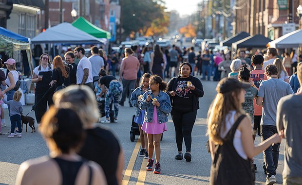 Neighborhood pride shines at Brookland Park Fest-Brookland Park Fest filled the boulevard with music, art and food as residents and visitors gathered Sunday, Nov. 9 for the annual community celebration. The free event, organized by the Brookland Park Business Association, showcased local businesses, artists and food vendors, along with musical performances, family activities and special events hosted by shops along Brookland Park Boulevard between Fendall and North avenues. Frankie Akande and her twin daughters, Bella and Henri Robertson, 9, navigate the
bustling festival street while enjoying ice cream. (Julianne Tripp Hillian)