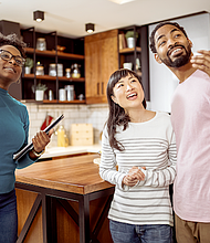 African American real estate agent showing house to multiracial couple, realtor telling clients about home advantages, interior designer discussing renovation ideas with homeowners.