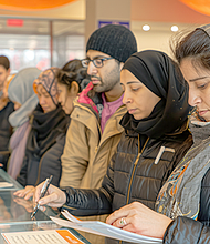 Refugees receiving legal assistance from volunteers, expressions of hope and worry, sense of seeking protection and rights, indoor setting with documents and legal advisors, focus on refugee rights