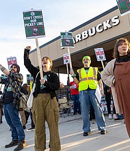 Kat Glynn and Beck Whittenton, Starbucks baristas, Olivia Geho with the
Virginia Education Association and Dustin Bixler, a Starbucks barista, cheer passing cars during a “Red Cup Day” rally Nov. 13 outside the 2309 W. Broad St. Starbucks to protest what they describe as the company’s union busting and its failure to reach a union contract.