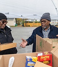 Hands and hearts at work as families receive holiday meals-Johnnie Thomas, left, and Lee Ford, right, members of the Bethlehem Baptist Church men’s fellowship group, hand out meal boxes and turkeys to local families on Nov 20. (photo by Julianne Tripp Hillian/Richmond Free Press)
