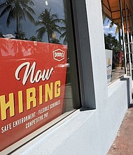 A 'Now Hiring' sign sits in the window of a Denny's restaurant on November 19 in Miami.