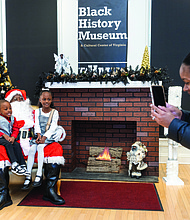 Soul of Christmas-Children and families visited the Black History Museum &
Cultural Center of Virginia on Nov. 29 for the annual Soul Santa Experience. The museum will host two more Saturdays, Dec. 6 and Dec. 13, from 11 a.m. to 3 p.m. as part of Community Access Days with free admission and optional donations. Attendees can hear holiday stories, join arts and crafts activities and browse the museum gift shop for items such as the Ebonyopoly board game. Okeira Lightfoot takes a photo of her children, Sir Lightfoot, 3 (left), and Laiyah
Edwards, 8 (right), with Soul Santa. (photo by Julianne Tripp Hillian/Richmond Free Press)