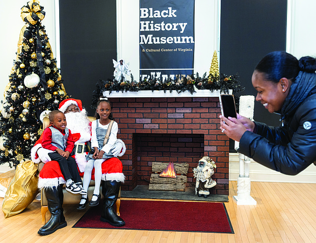 Soul of Christmas-Children and families visited the Black History Museum &
Cultural Center of Virginia on Nov. 29 for the annual Soul Santa Experience. The museum will host two more Saturdays, Dec. 6 and Dec. 13, from 11 a.m. to 3 p.m. as part of Community Access Days with free admission and optional donations. Attendees can hear holiday stories, join arts and crafts activities and browse the museum gift shop for items such as the Ebonyopoly board game. Okeira Lightfoot takes a photo of her children, Sir Lightfoot, 3 (left), and Laiyah
Edwards, 8 (right), with Soul Santa. (photo by Julianne Tripp Hillian/Richmond Free Press)