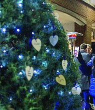 Lighting the way for healing and change-Henrico County’s held its annual Candlelight & Ribbon Tying Ceremony on Tuesday to honor homicide victims. Sponsored by the Henrico County Commonwealth’s Attorney’s Victim/Witness Program, the event featured prayer, remarks from friends and family of the deceased, a memorial board of photographs and a memorial tree where participants placed the names of those they have lost. Early reports show the county has recorded just two homicides through December 2025, down from 22 during the same period last year — a potential 91% decrease if the trend holds through year’s end. Nicole Totten shares the Victims’ Rights memorial tree at Henrico County’s annual Attendees pause at the memorial board displaying photos of loved ones. ceremony as she remembers her niece, Diamond Cox. (Photo by Julianne Tripp Hillian/Richmond Free Press)
