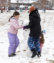 First snow, first fun-At Forest Hill Park, friends Campbell, Charley and Mariel team up to build a snowman. (photo by Julianne Tripp Hillian/Richmond Free Press)