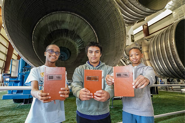 Houston ISD students pose in front of the Saturn V rocket at the George W.S. Abbey Rocket Park during an October tour, holding journals provided by the Cactus Jack Foundation. (Photo Courtesy of Space Center Houston).