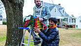 Chris Miller hangs a wreath from a ladder as Dolores W. Whitaker, 90, looks on along the 1300 block of Hampton Street. Whitaker has decorated the trees on her block for the past 30 years.