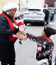Holiday convoy delivers smiles in Gilpin Court-During the FRIENDS Association for Children’s annual holiday vehicle parade Tuesday morning along St. John Street in Gilpin Court, vehicles from Richmond Fire and Police, Richmond Ambulance and local car clubs circle neighborhoods in Gilpin Court and Church Hill, distributing stuffed animals and other gifts to children along the route. Richmond School Board member Cheryl Burke hands a stuffed reindeer to Sha’vez Pressley, 6, and other children along St. John Street in Gilpin Court. (photo by Julianne Tripp Hillian/Richmond Free Press)