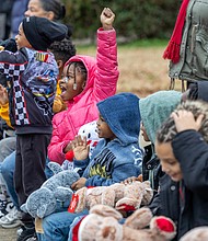 Friendly parade-Aloria Scott-Roswell, 7, joins cheers from a group of
children as vehicles pass during the FRIENDS Association for Children annual Holiday Vehicle Parade on Tuesday morning along St. John Street in Gilpin Court. (photo by Julianne Tripp Hillian/Richmond Free Press)