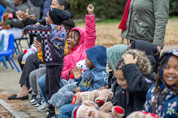 Friendly parade-Aloria Scott-Roswell, 7, joins cheers from a group of
children as vehicles pass during the FRIENDS Association for Children annual Holiday Vehicle Parade on Tuesday morning along St. John Street in Gilpin Court. (photo by Julianne Tripp Hillian/Richmond Free Press)