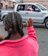 Holiday convoy delivers smiles in Gilpin Court-During the FRIENDS Association for Children’s annual holiday vehicle parade Tuesday morning along St. John Street in Gilpin Court, vehicles from Richmond Fire and Police, Richmond Ambulance and local car clubs circle neighborhoods in Gilpin Court and Church Hill, distributing stuffed animals
and other gifts to children along the route. Precious, 9, greets Santa as he rides in the passenger seat. (photo by Julianne Tripp Hillian/Richmond Free Press)