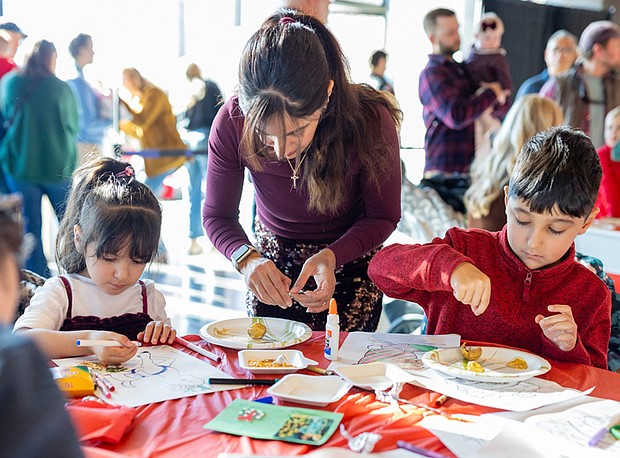 Families meet Santa at American Civil War Museum-Families gathered at the American Civil War Museum on Saturday, Dec. 20, for a holiday celebration featuring a visit from Santa, arts and crafts for children, and a chance to take care of last-minute holiday requests. Behnaz Bashiri makes gold chestnut ornaments and other crafts with Nika, 4, and Micah, 7. (photo by Julianne Tripp Hillian/Richmond Free Press)