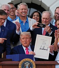 President Donald Trump holds his signed signature bill of tax breaks and
spending cuts surrounded by members of Congress at the White House in Washington, on July 4.