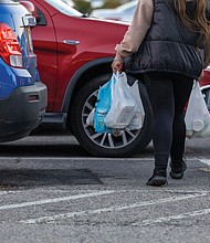 A shopper exits a grocery store with plastic bags, which will be subject to a new tax taking effect statewide Jan. 1. Retailers will be required to collect a 5-cent fee for each disposable plastic bag they provide customers.