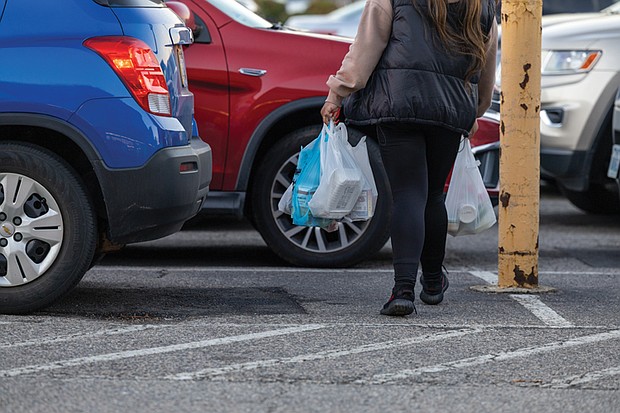 A shopper exits a grocery store with plastic bags, which will be subject to a new tax taking effect statewide Jan. 1. Retailers will be required to collect a 5-cent fee for each disposable plastic bag they provide customers.