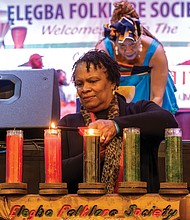 Honoring heritage with community and celebration-Nanette Kenney of Henrico lights the candle on the Kinara representing the fourth Kwanzaa principle, Ujamaa, or cooperative economics, focused on building and maintaining Black businesses, as Janine Bell pours libation. (photo by Sandra Sellars/Richmond Free Press)