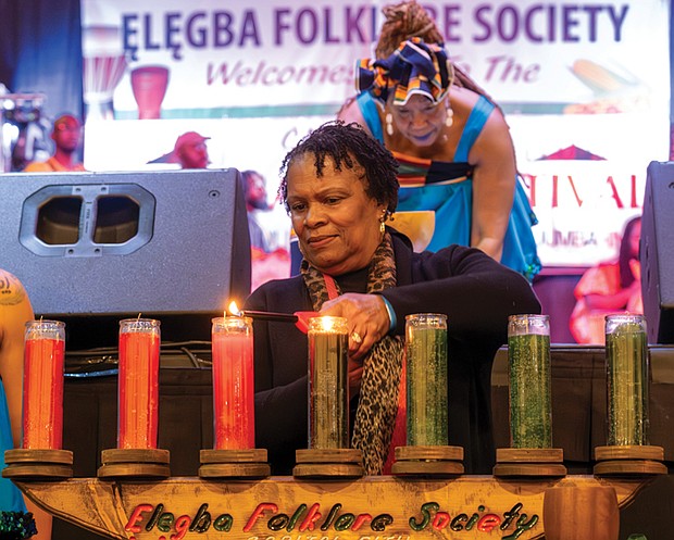 Honoring heritage with community and celebration-Nanette Kenney of Henrico lights the candle on the Kinara representing the fourth Kwanzaa principle, Ujamaa, or cooperative economics, focused on building and maintaining Black businesses, as Janine Bell pours libation. (photo by Sandra Sellars/Richmond Free Press)