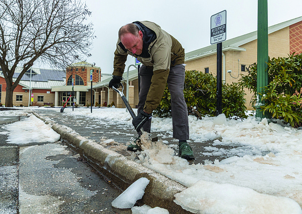 Digging out-Jeff Stumb, whose daughter is a fourth grader at Linwood Holton Elementary School, grabs a shovel Tuesday, Feb. 3 to help clear icy sidewalks around the school. Other local parents joined him, pitching in to make the walkways safe ahead of students’ return on a two-hour delay Wednesday, Feb. 4, after more than a week out of school because of recent severe weather. (photo by Julianne Tripp Hillian/Richmond Free Press)