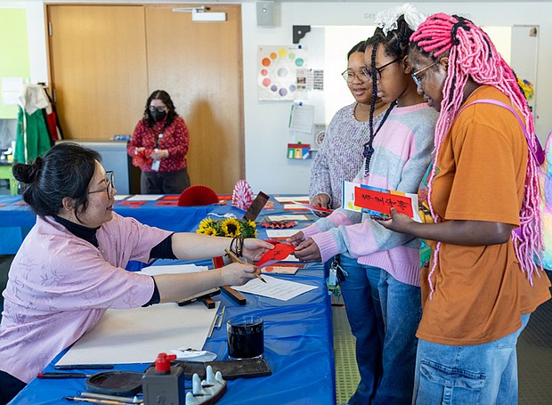 Lunar New Year celebrated at VMFA-The Virginia Museum of Fine Arts celebrated the Lunar New Year on Saturday, Feb. 7 with the museum’s annual ChinaFest celebration. The “Year of the Fire Horse” event featured art activities, dance and music performances, kung fu and calligraphy demonstrations. DJ Lomax, 31, her 11-year-old daughter, Aubrey Allen,
and friend Brianna Young, 21, have their names written in
Chinese calligraphy by Dr. Jing Shui. (photo by Julianne Tripp Hillian/Richmond Free Press)