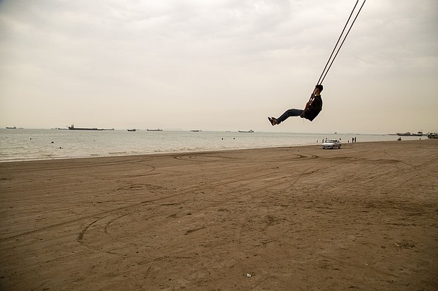 A man swings from a giant rope swing on the beach as ships are anchored near the shoreline on April 22 in Bandar Abbas, Iran. Bandar Abbas is a port city and the capital of Hormozgan Province, along the Persian Gulf and Strait of Hormuz.