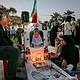 Relatives sit by the grave of a deceased relative, as people gather to mourn at the cemetery of Minab City on May 14, in Minab, Iran.