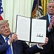 President Donald Trump holds a signed executive order about vaccines as Health and Human Services Secretary Robert F. Kennedy Jr. looks watches on August 10 in the Oval Office.