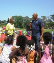Children look on as Catherine Simmons (left)  and C.A.P.S. Director Ron Holt chat during the Save the Children95 annual picnic. (Photo by Thelma Sardin)