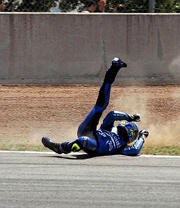 A motorcyclist in full protective gear slides along the tarmac after falling off his bike. (photo by Franc)